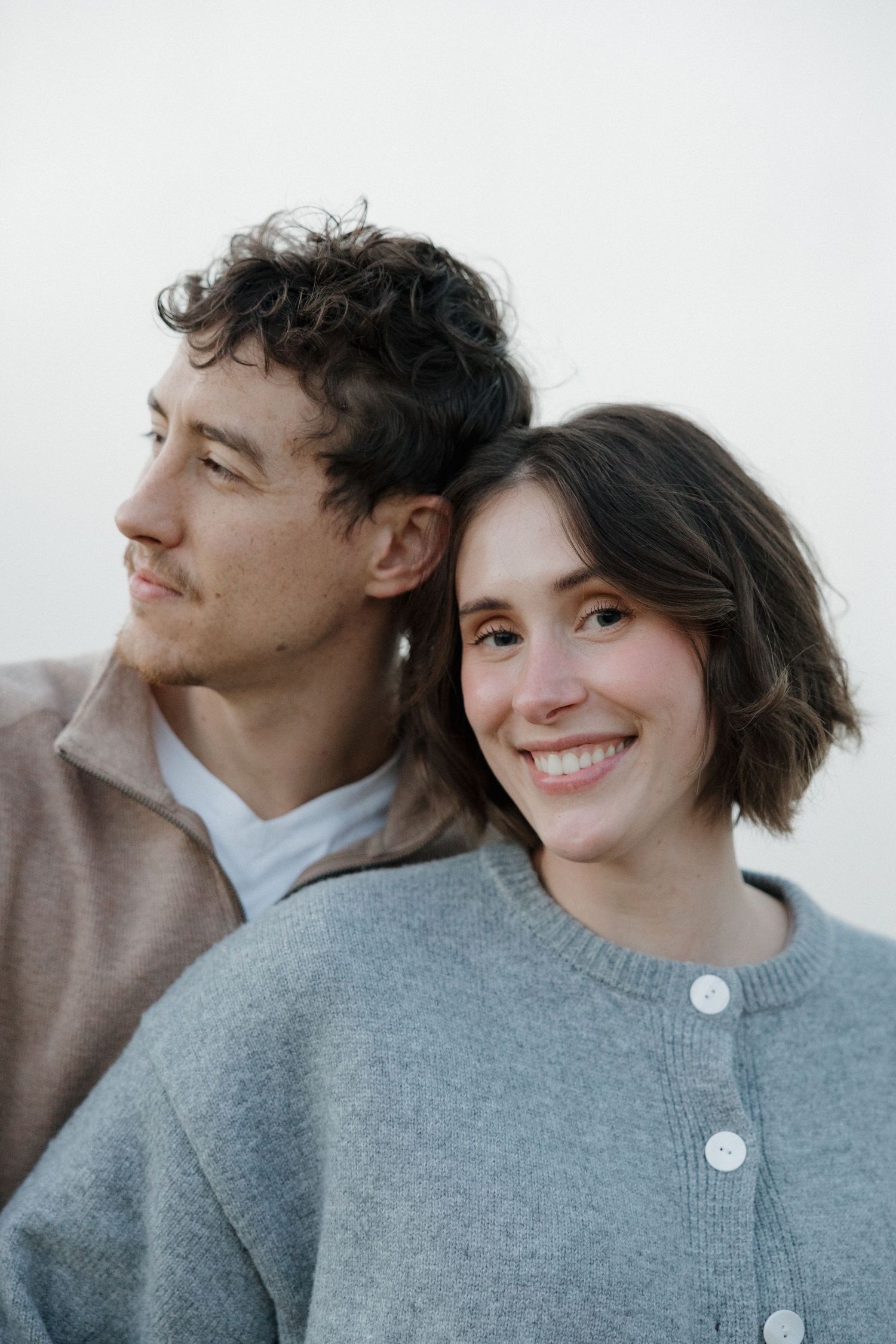 Close-up photos capture a couple in gray sweaters sharing intimate moments together.