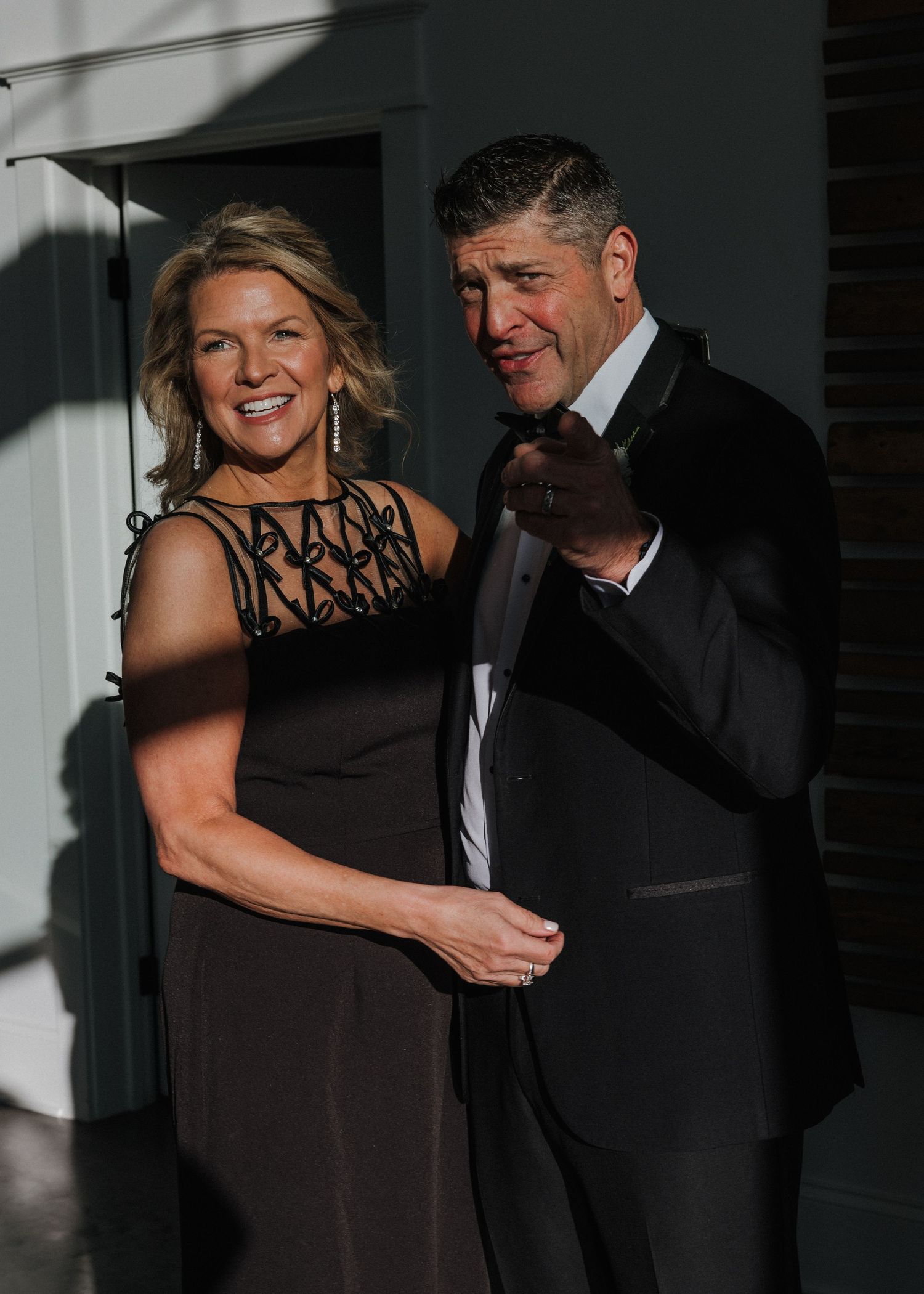 A couple dances together in formal attire, with the woman wearing a black dress and the man in a dark suit.