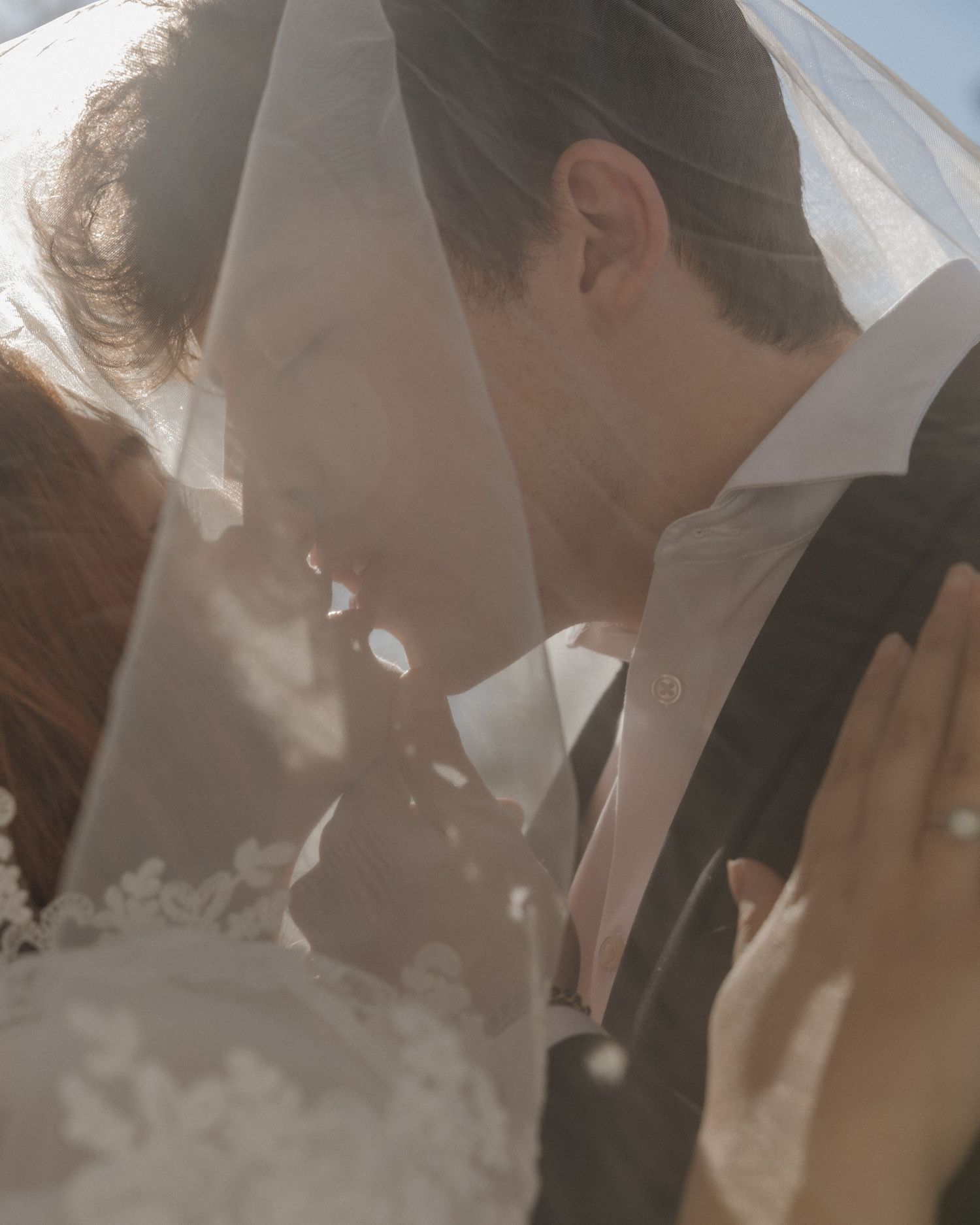 A romantic wedding ceremony moment captured in soft, dreamy lighting with guests looking on in the background.