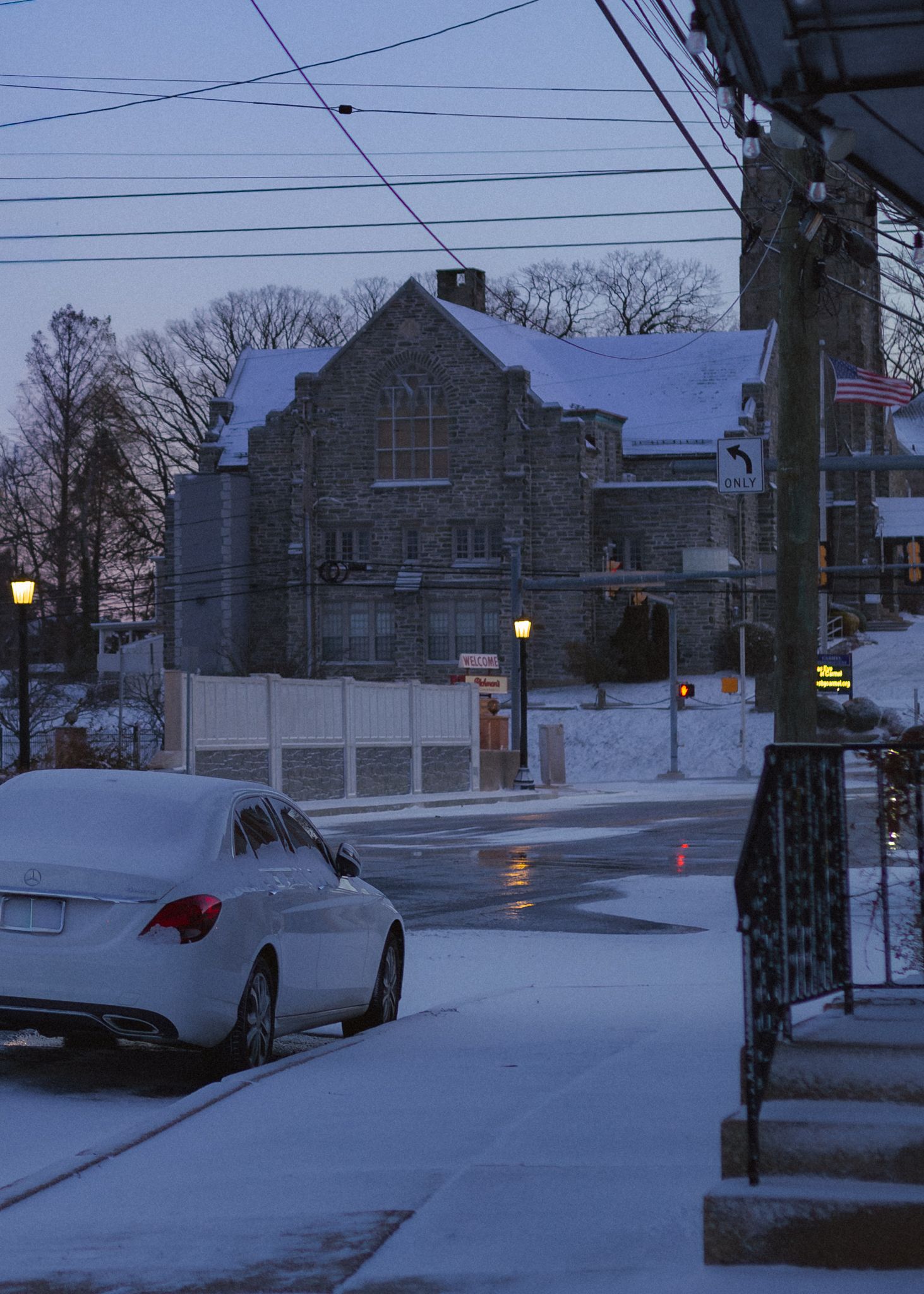 A snowy winter street scene at dusk with a stone church and parked cars visible through multiple similar views.