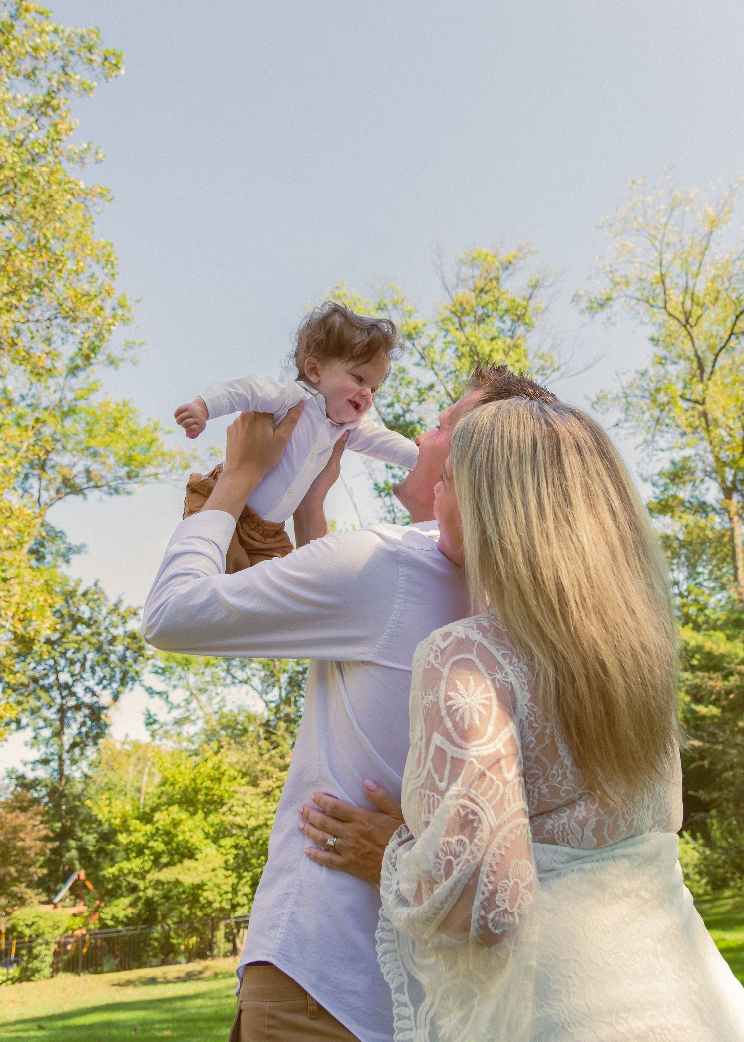 A couple dancing together on a sunny day in a grassy outdoor setting with trees in the background.