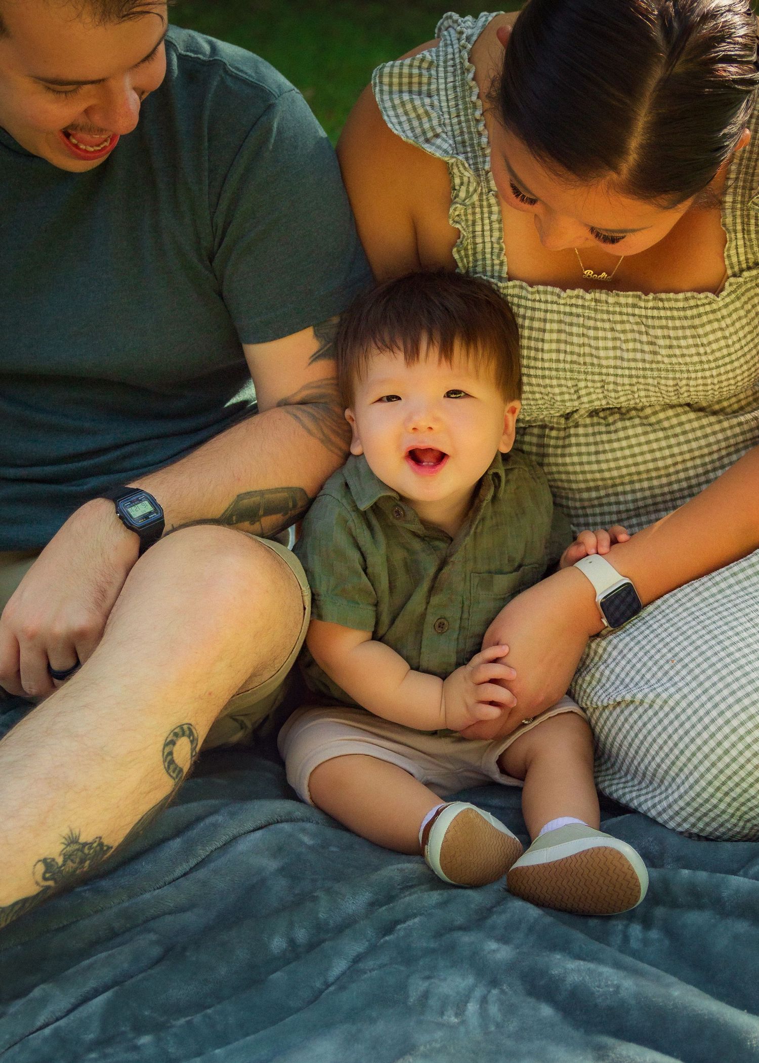 A sequence of photos showing a toddler in green clothing being tickled and laughing while sitting on a gray blanket.