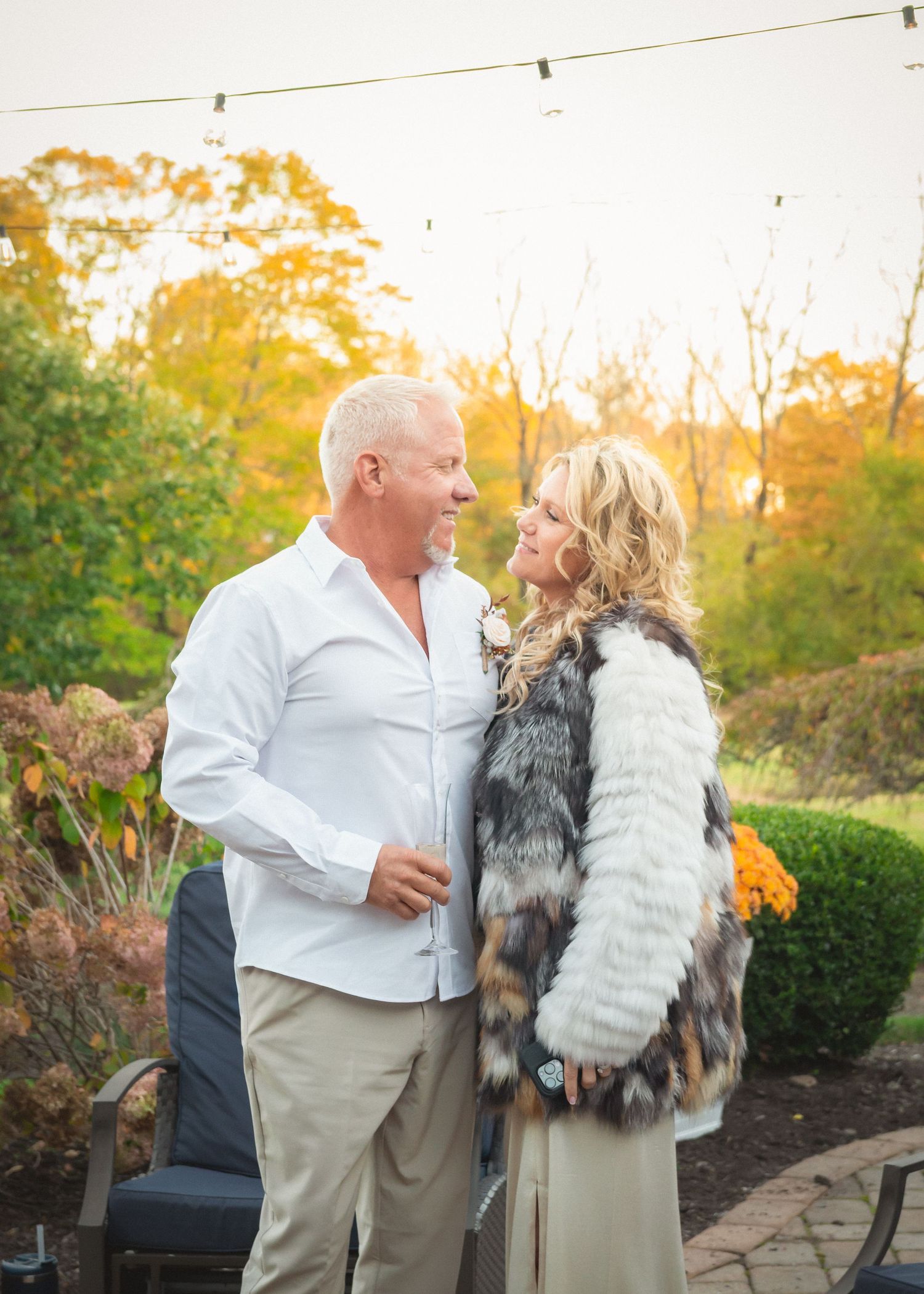 A couple shares a romantic moment in a garden during golden hour sunset while wearing coordinating white outfits.