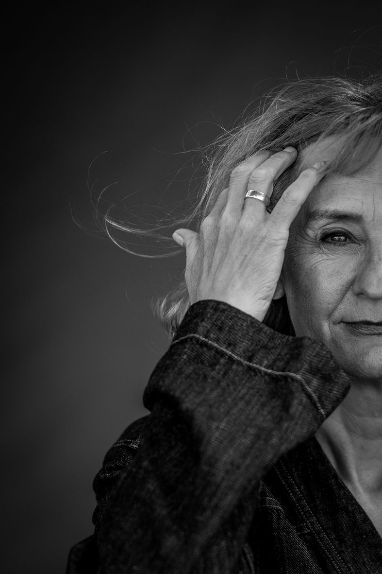 Schwarz-Weiß-Porträt einer Frau mit halbem Gesicht, sichtbarem Auge und Hand mit Ehering im Haar.