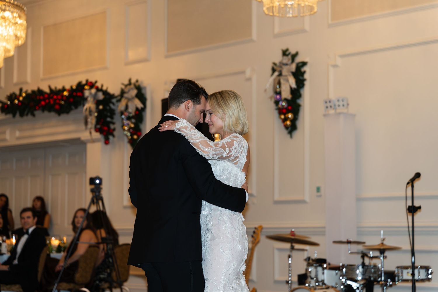 Bride and groom share their first dance in an elegant ballroom decorated with Christmas garland at their winter wedding.