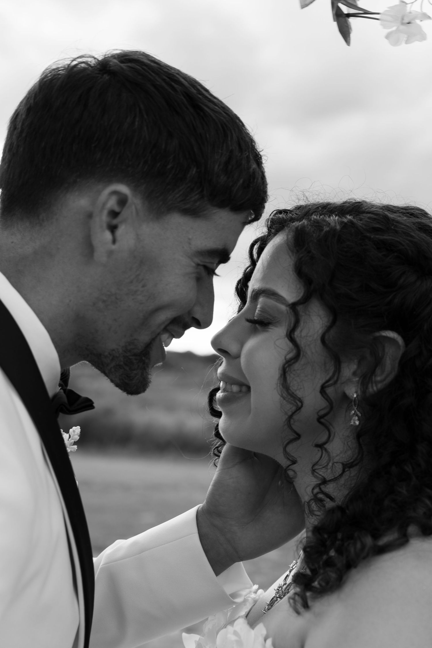 Black and white photo of a smiling bride and groom sharing a romantic moment on their wedding day.