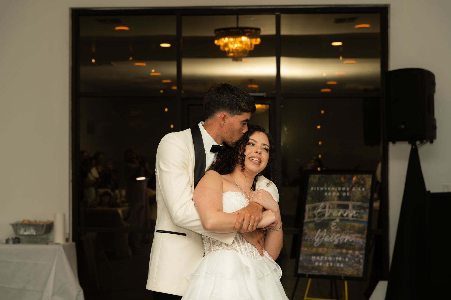 Bride and groom share a romantic first dance embrace inside elegant wedding reception venue.