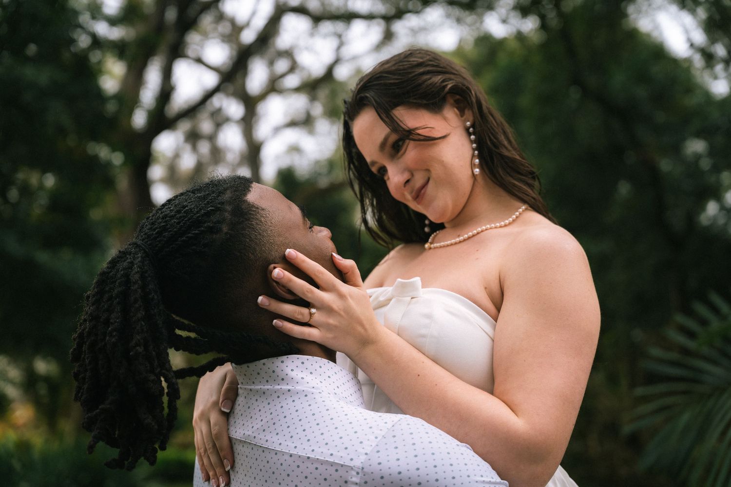 Romantic couple in white wedding attire embracing in a lush garden setting during their special day.