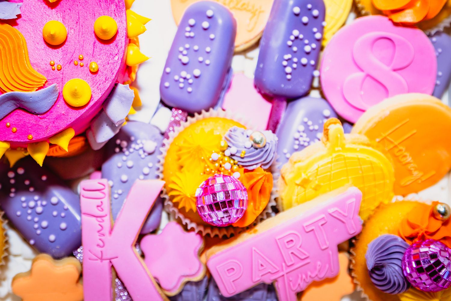 Colorful assortment of decorative cookies in purple, pink, and orange.