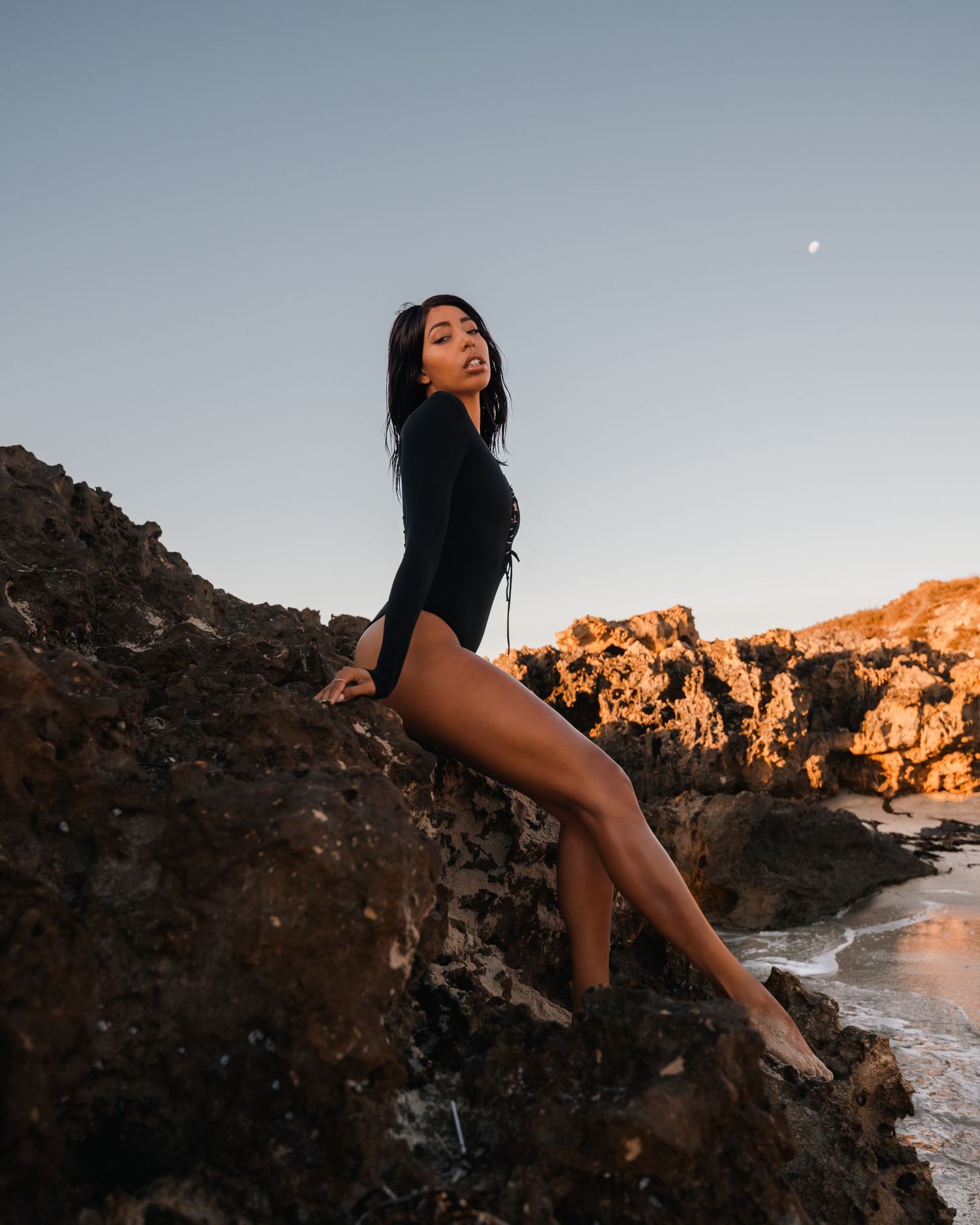 Sunset photoshoot at a rocky beach with dramatic cliffs and ocean views.