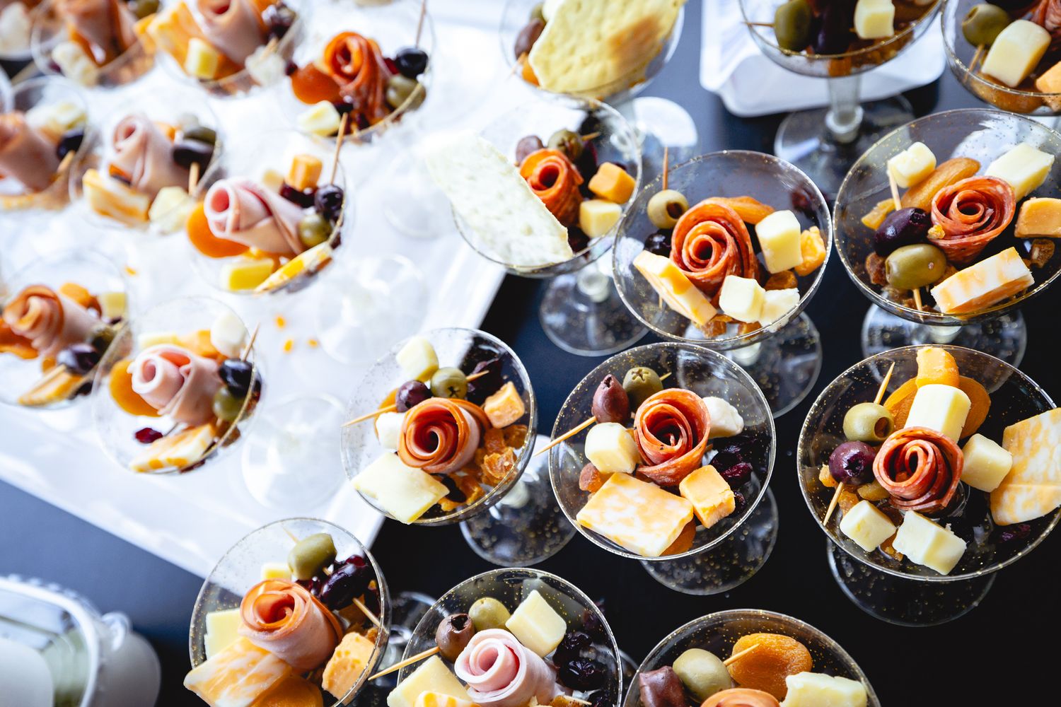 Elegant appetizers and hors d'oeuvres arranged on black plates for a catered event.