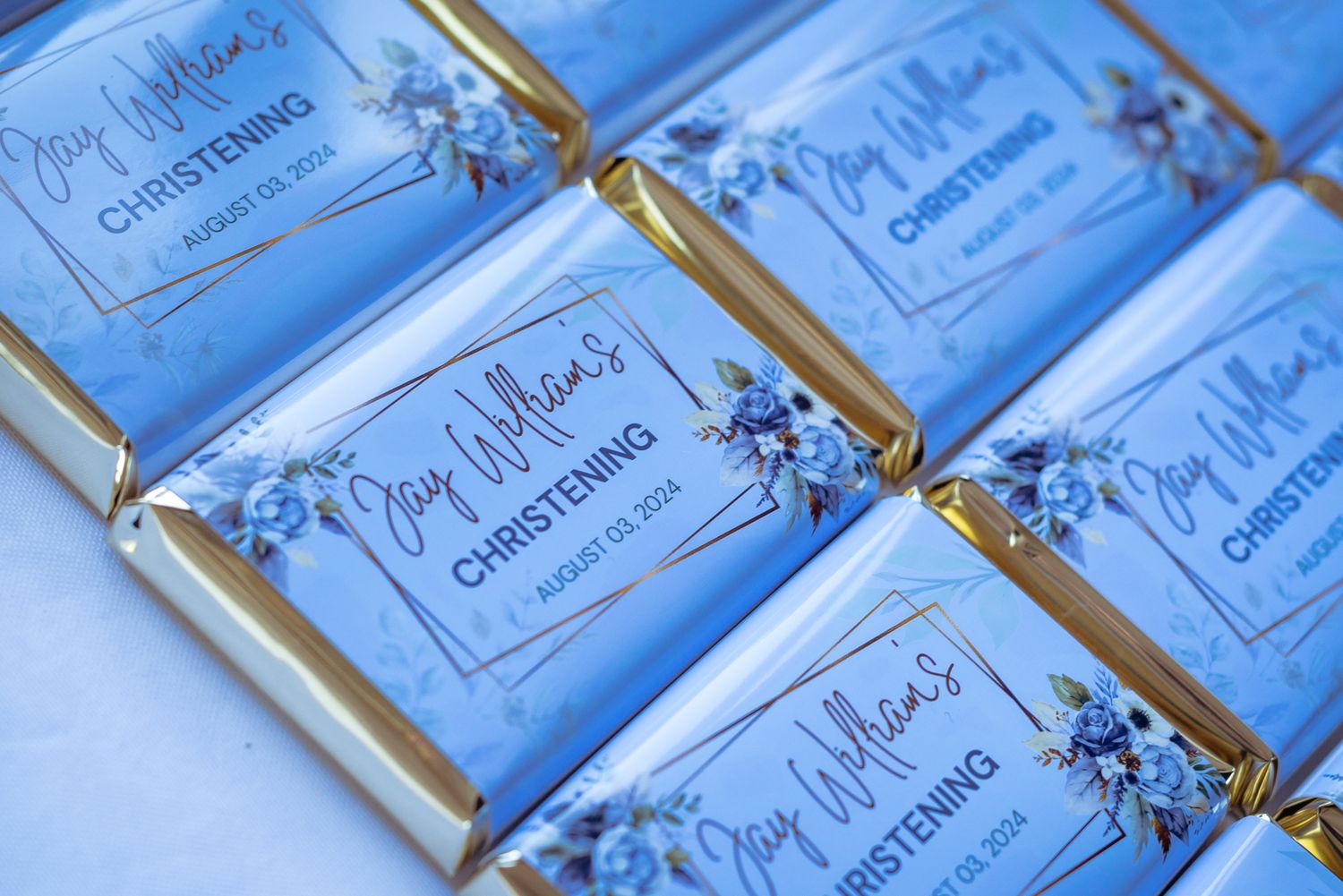 Close-up of blue wedding invitations with gold trim laid out in a row.