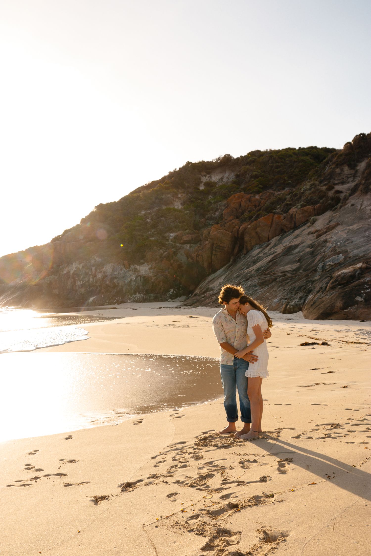 A couple enjoys a romantic sunset moment on a secluded beach.