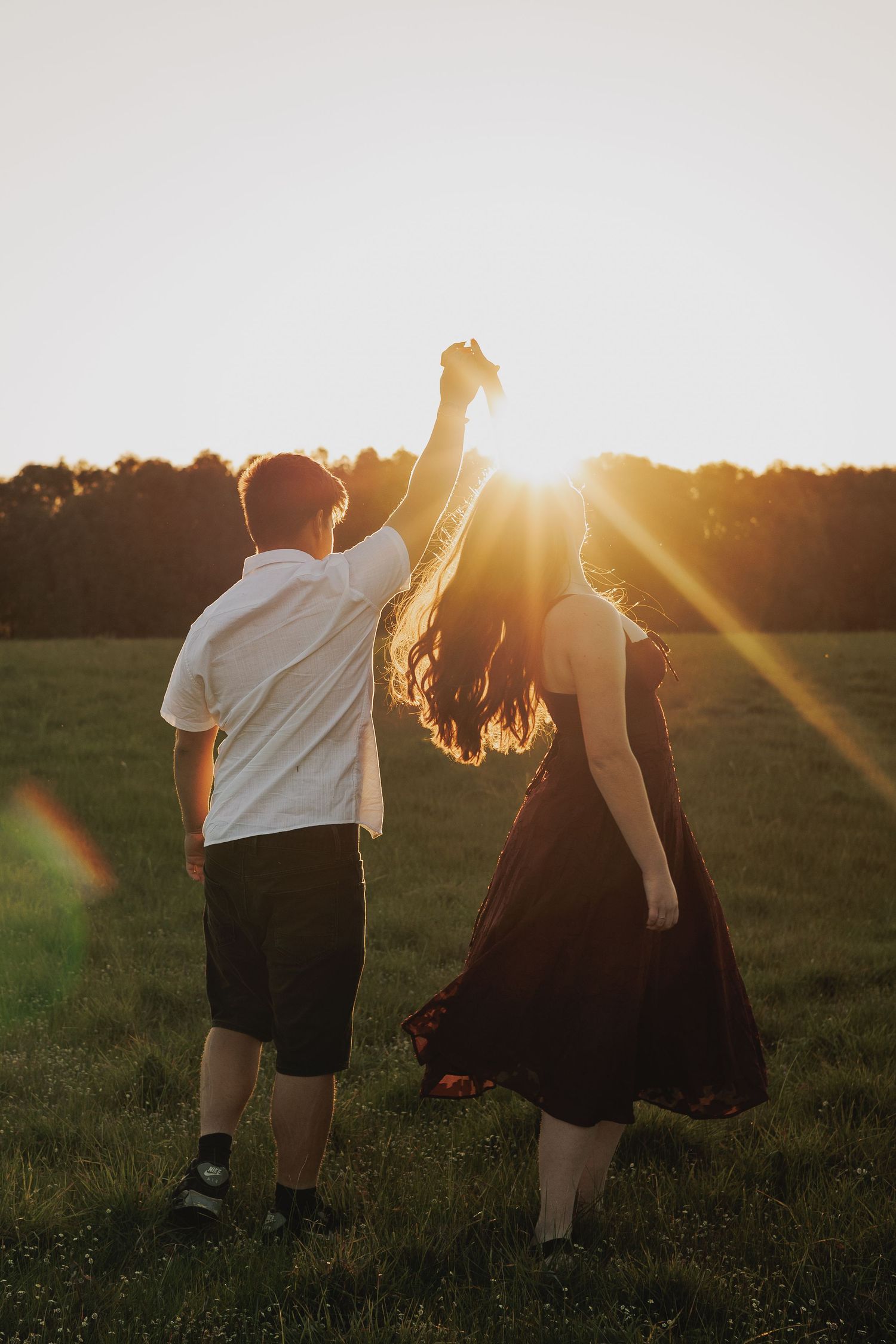 Silhouettes of people walking in a field during golden hour sunset.