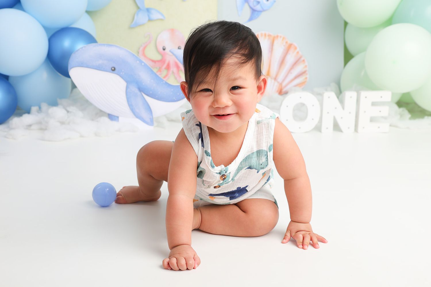 First birthday cake smash photo session with ocean themed backdrop and decorations.