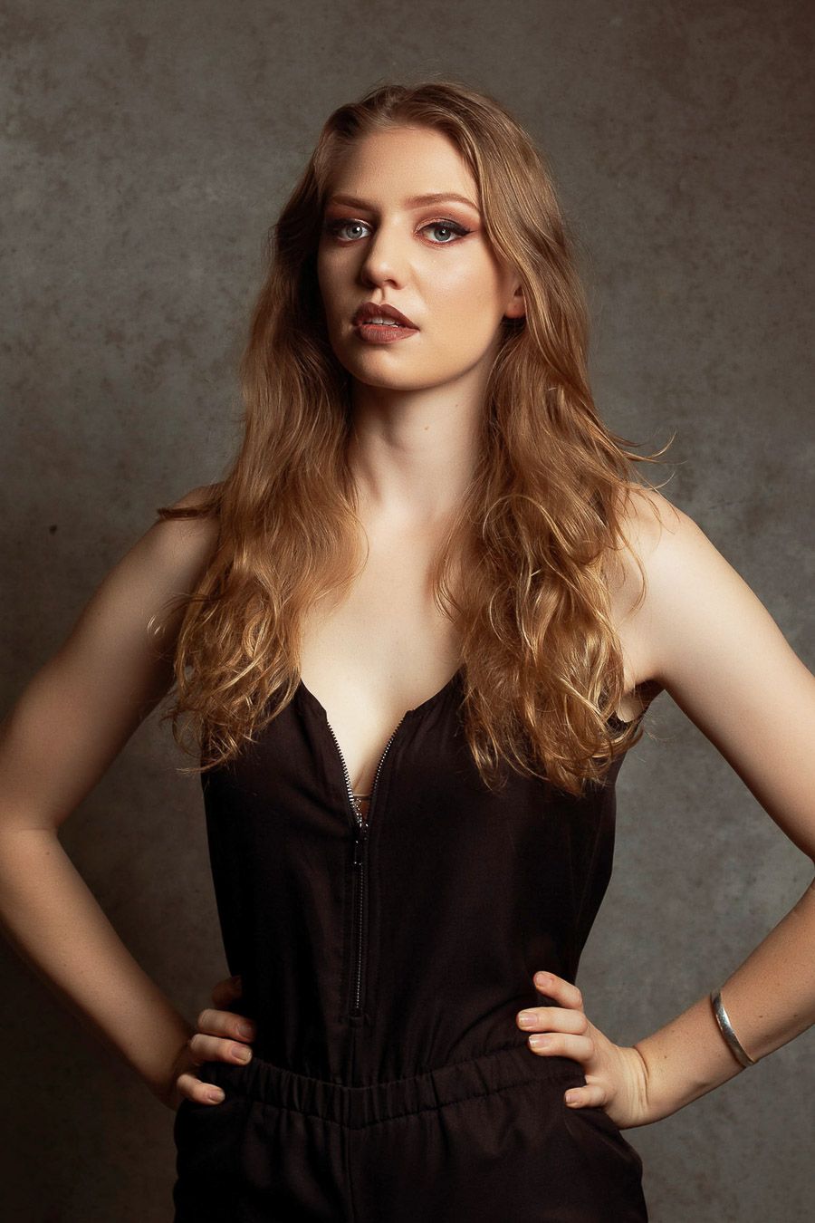 Portrait series showing model in black dress against dark textured background.