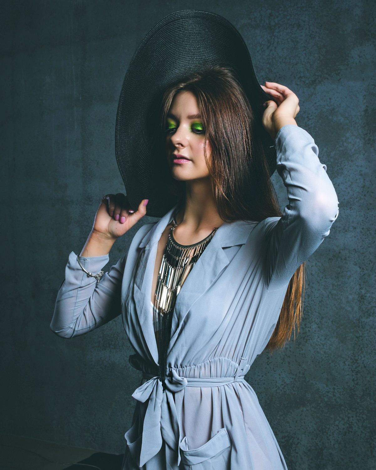 Moody fashion portraits in flowing gray dress against dark background.