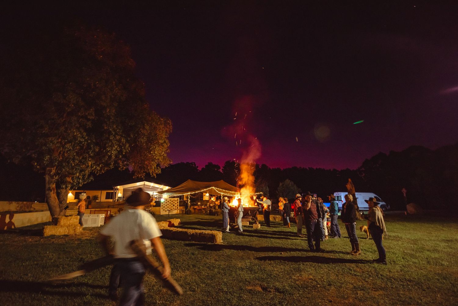 Twilight gathering at an outdoor event venue with string lights.