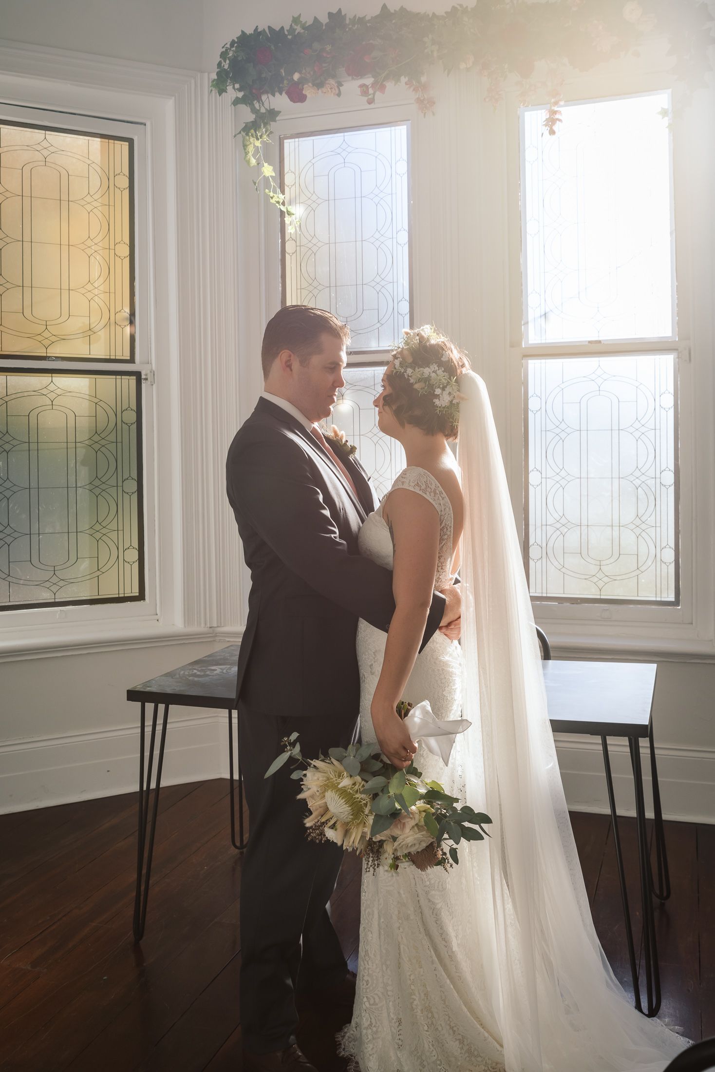 A romantic wedding moment captured by a bright window with elegant decor and soft lighting.