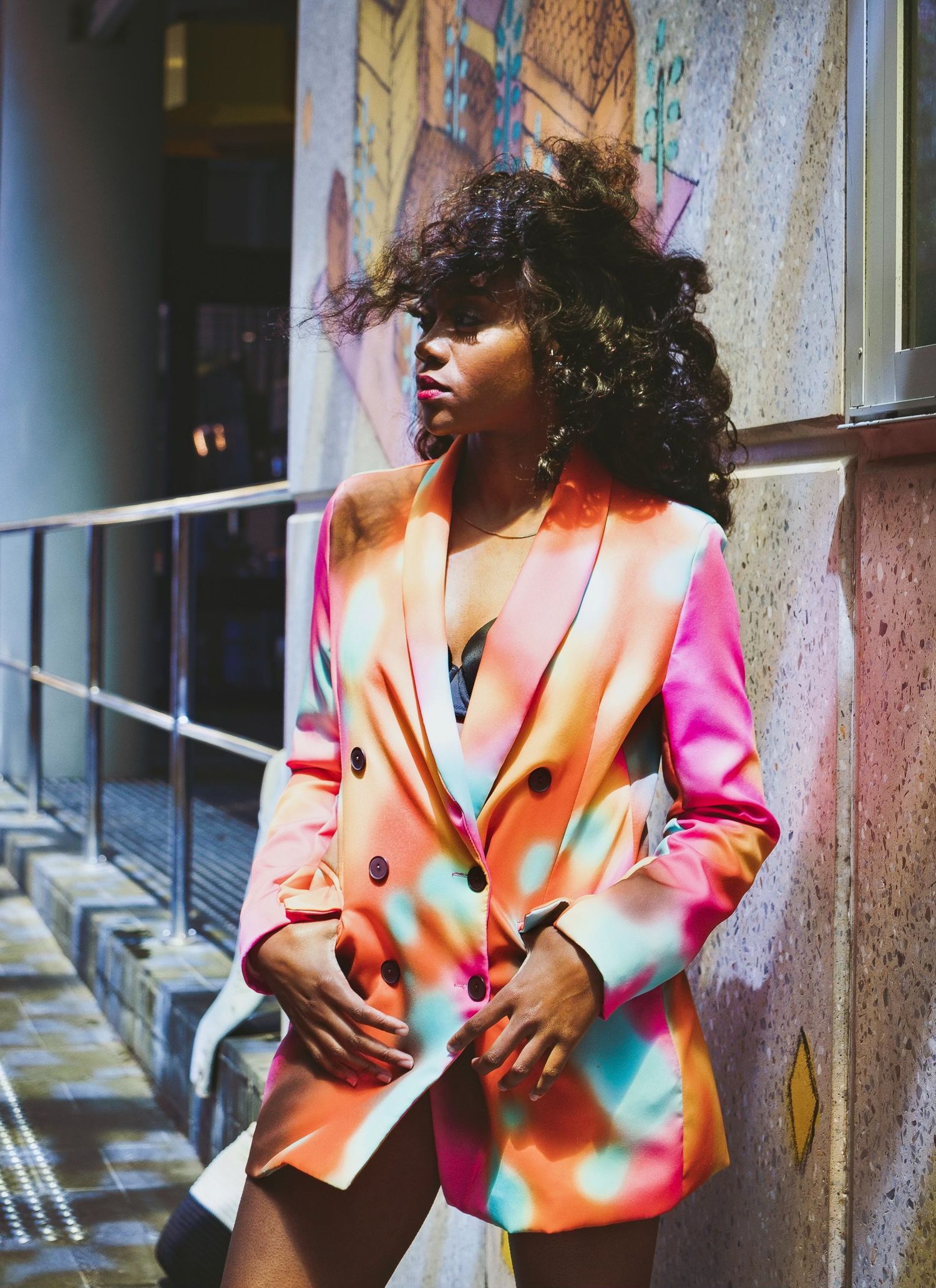 Fashion model in vibrant color-block blazer poses in urban setting.