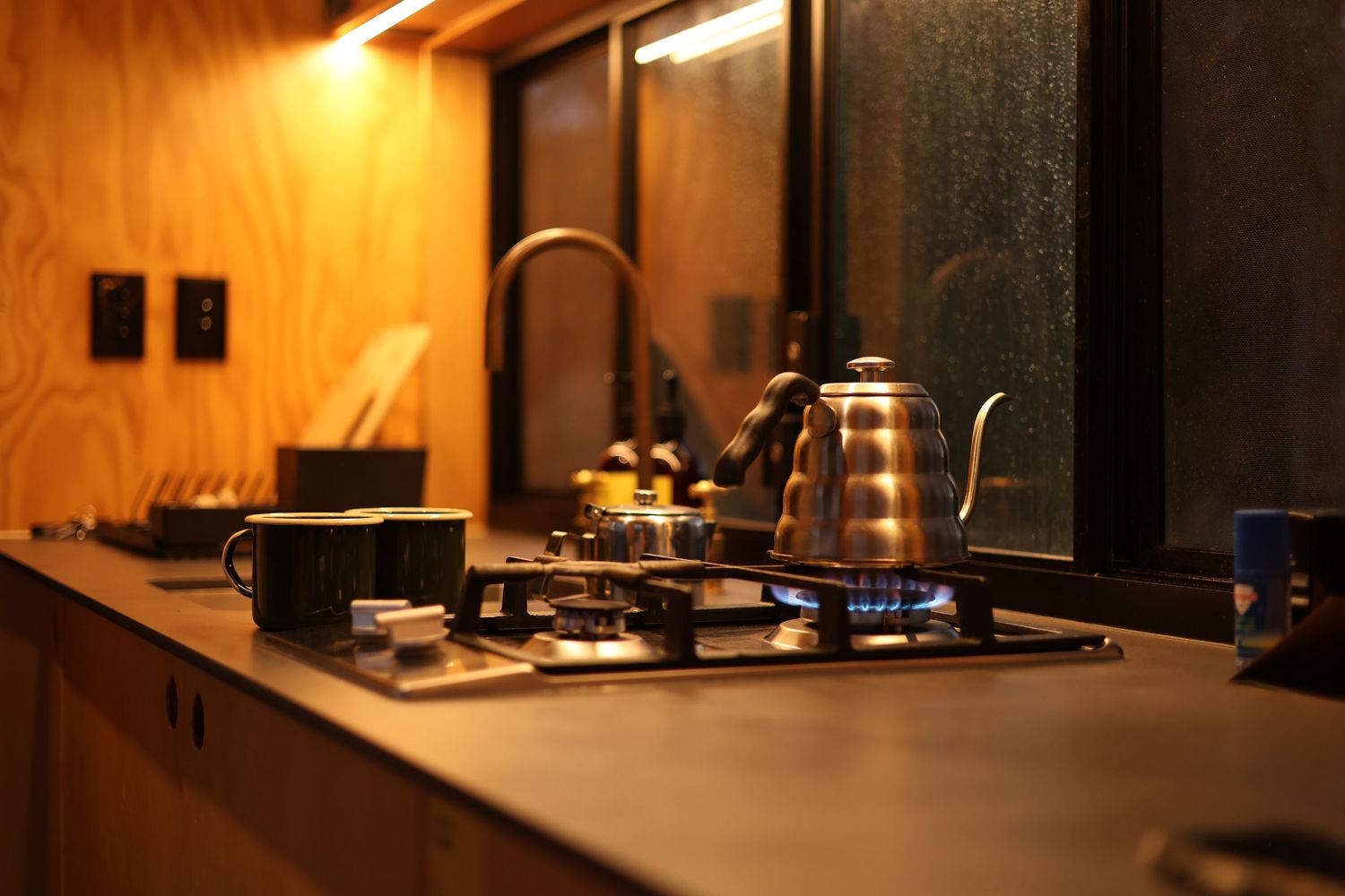 Counter workspace under soft amber lighting with sleek modern appliances and dark background.