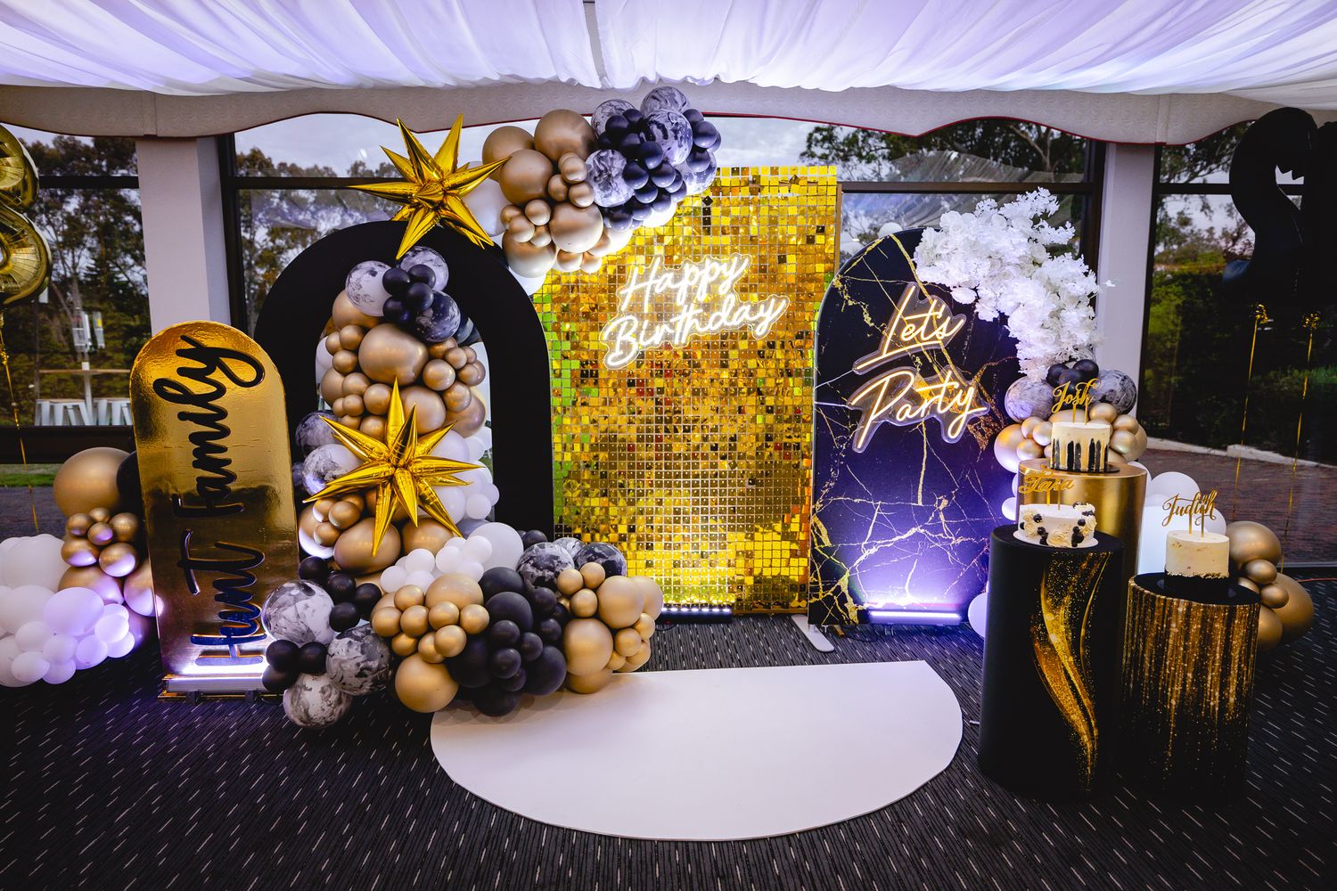 Event decor featuring white draping and gold balloon arrangements.
