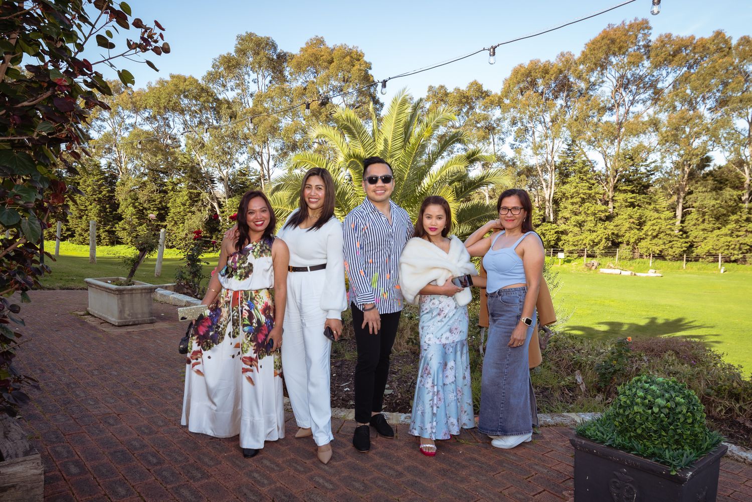 Scenic outdoor party setting with guests gathered on a grassy lawn.