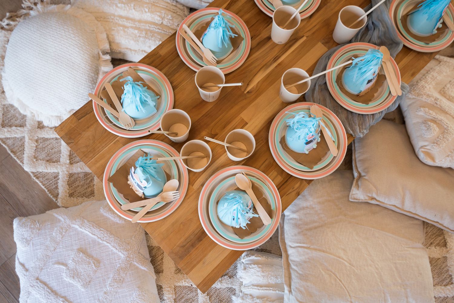 Place settings with blue decorative elements arranged on a wooden table.