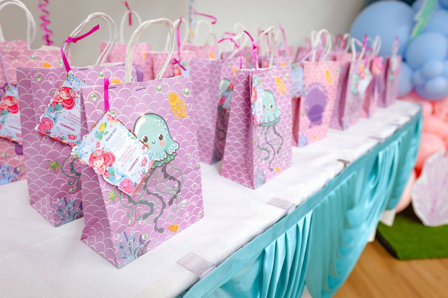 Row of pink floral gift boxes arranged on a turquoise tablecloth.