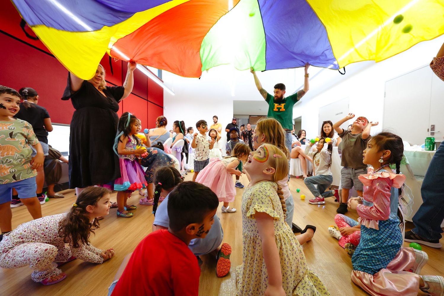 Children playing with colorful parachute fabric during group activity.