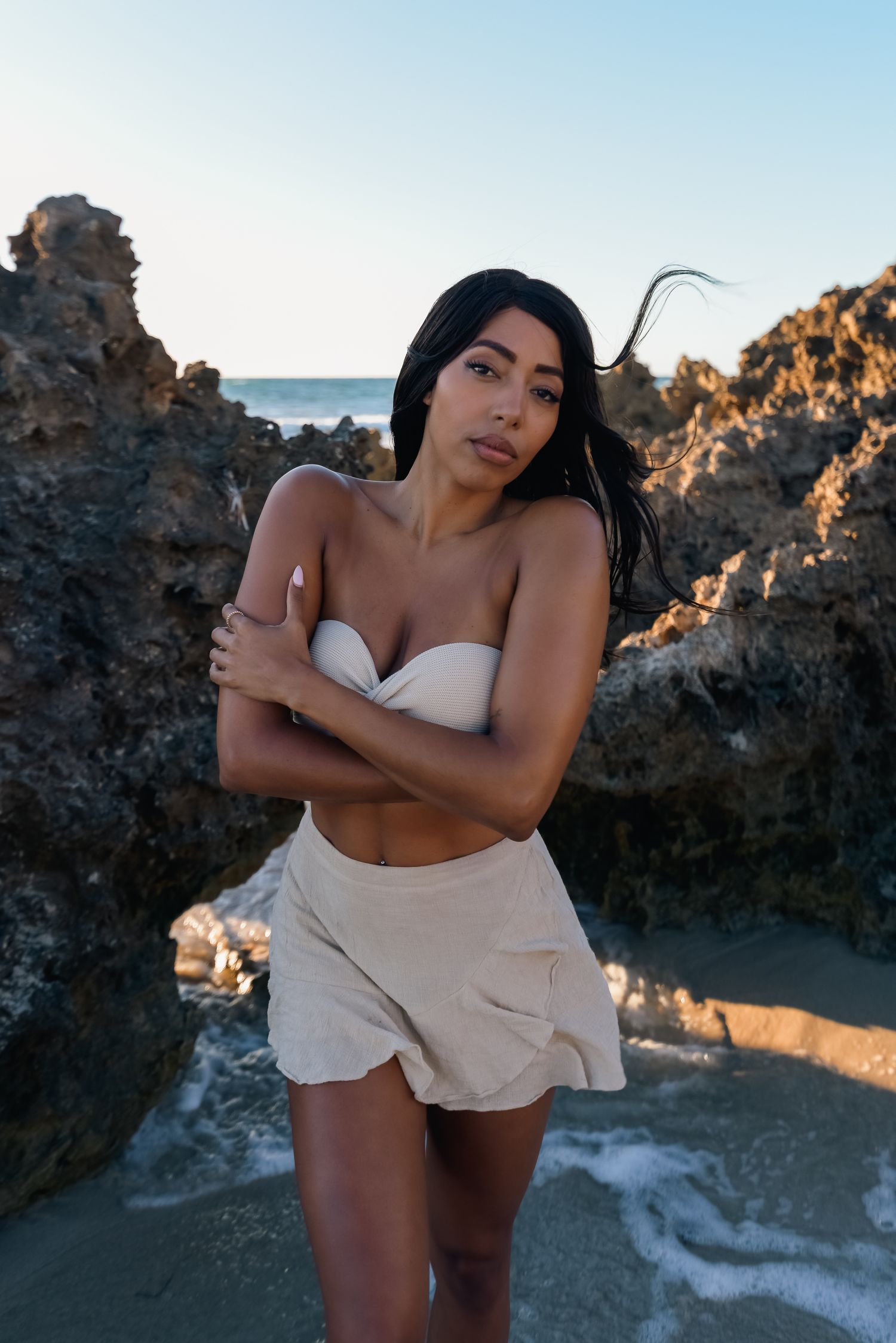 Dramatic coastal photoshoot featuring rocky cliffs and ocean backdrop at sunset.
