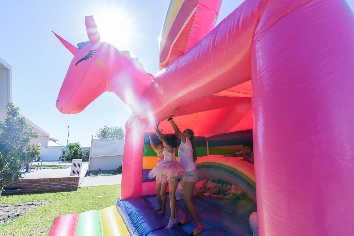 Pink and purple inflatable bounce houses at an outdoor party event.