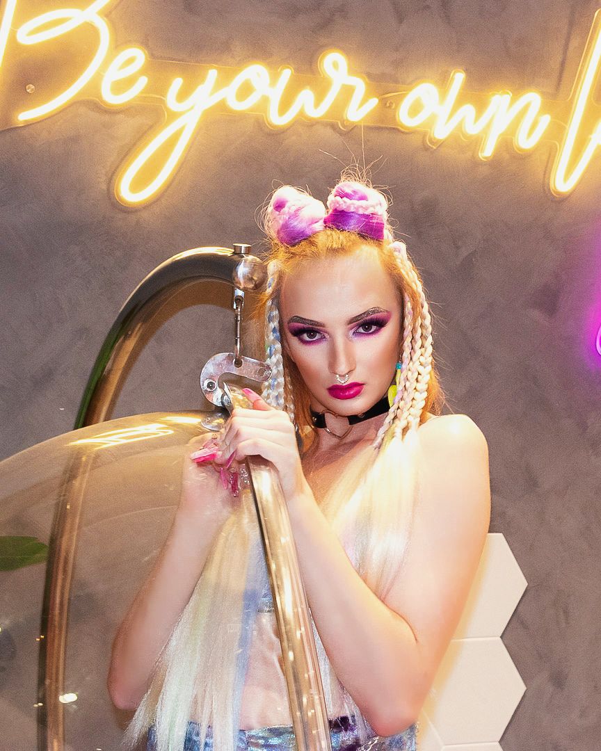 Glamorous nightclub photoshoot with neon lights and dramatic makeup.
