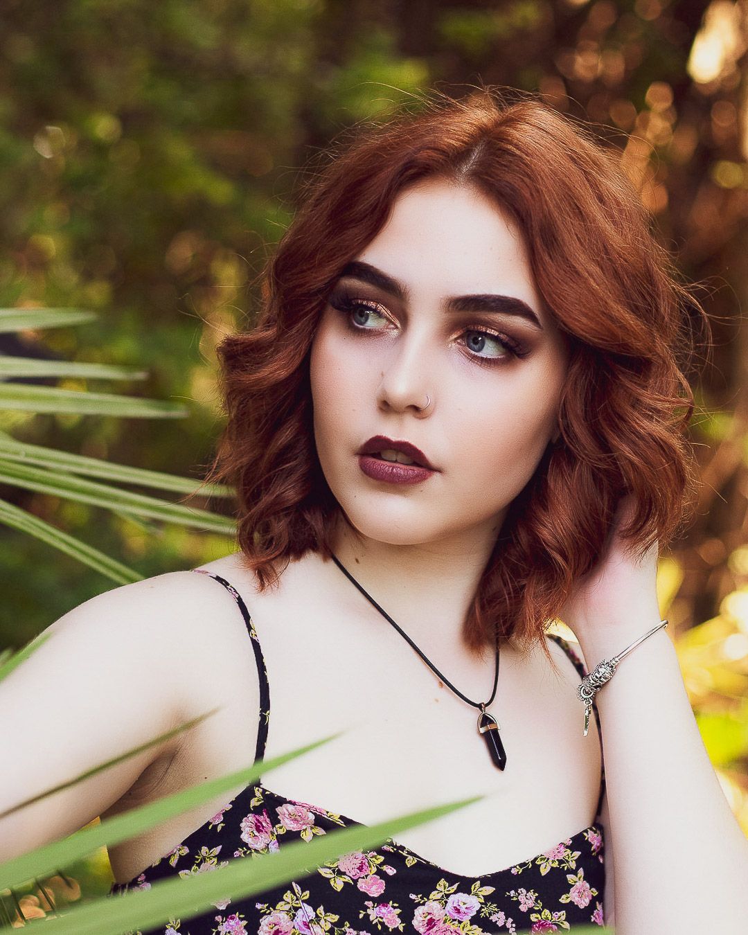 Fashion portrait series featuring floral dress and dramatic makeup in outdoor setting.