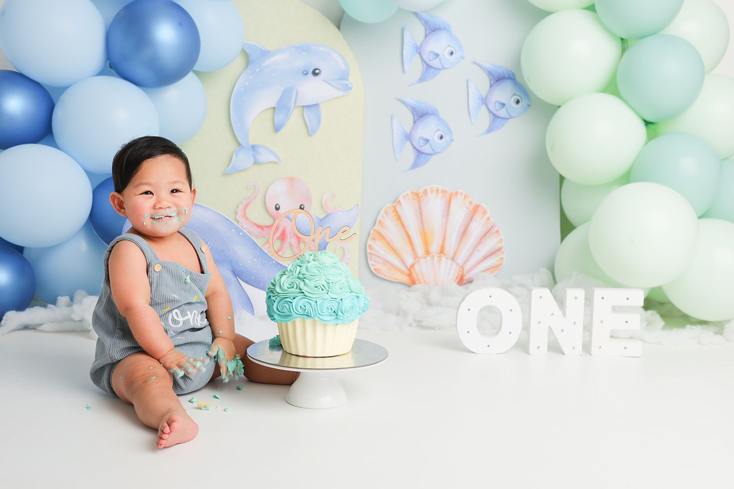 Ocean themed first birthday setup with blue balloons and decorative sea creatures.