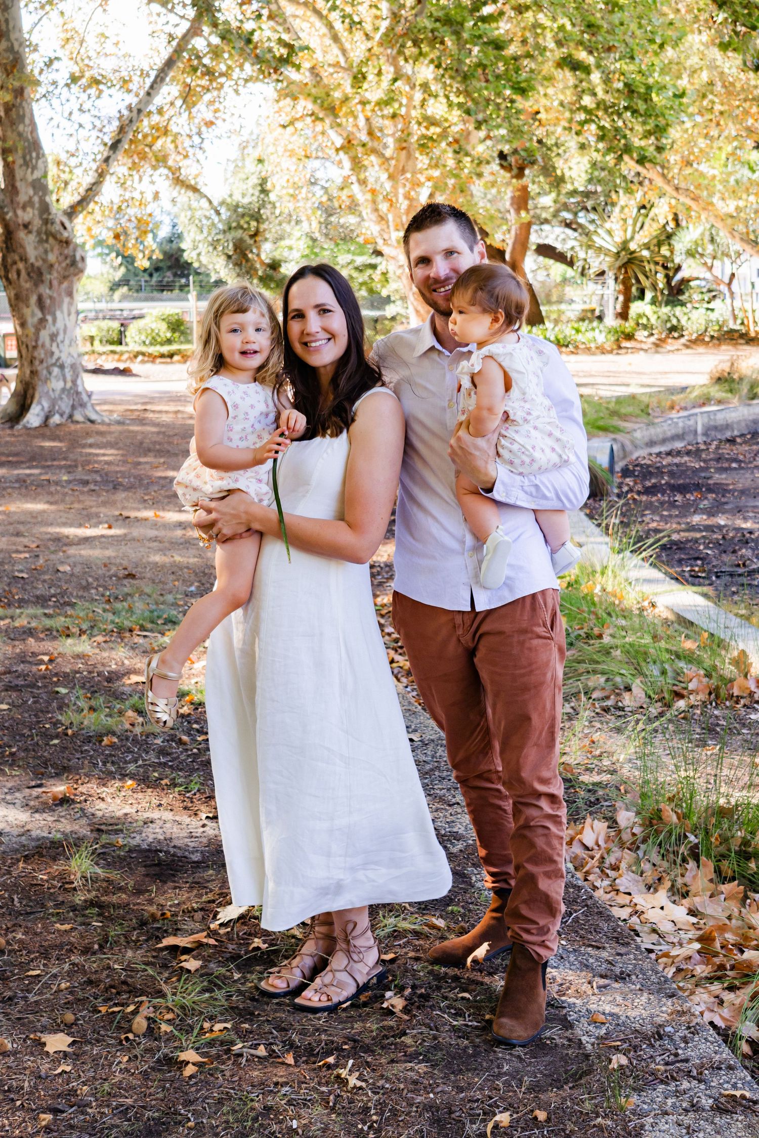Family group poses together on autumn path with fallen leaves.