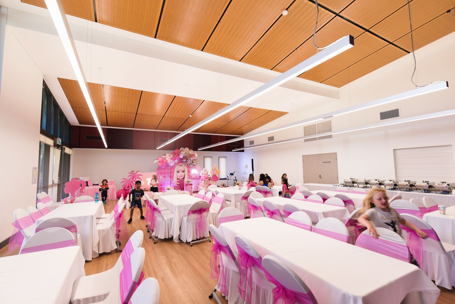 Modern event space interior with wooden ceiling and pink accent lighting.