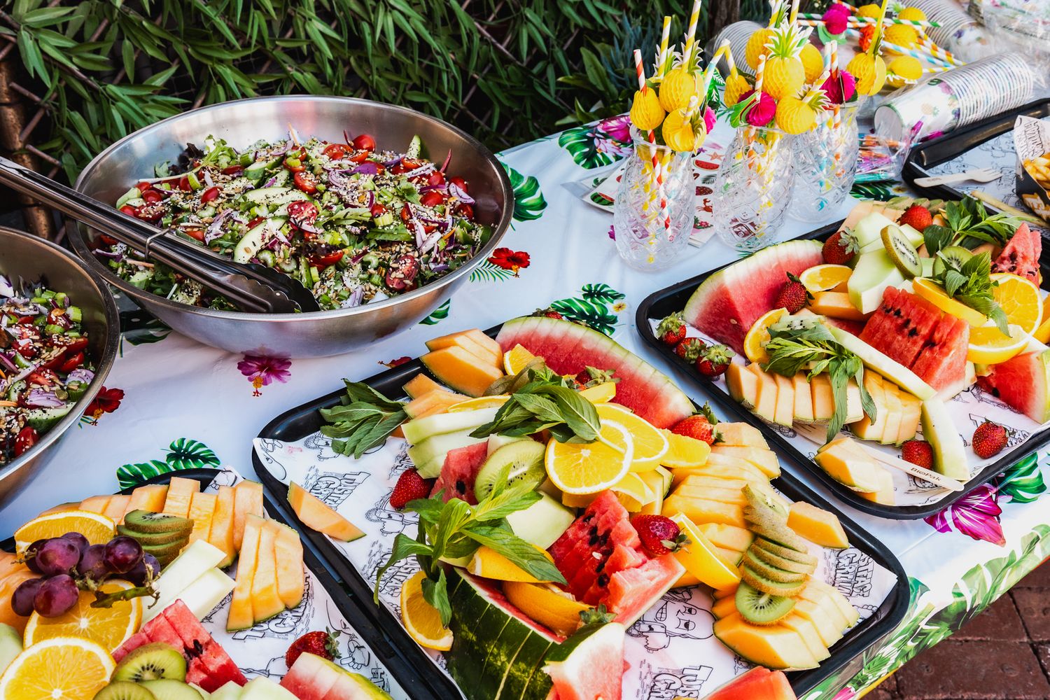 Fresh fruit and vegetable platters arranged on a buffet table with colorful presentation.