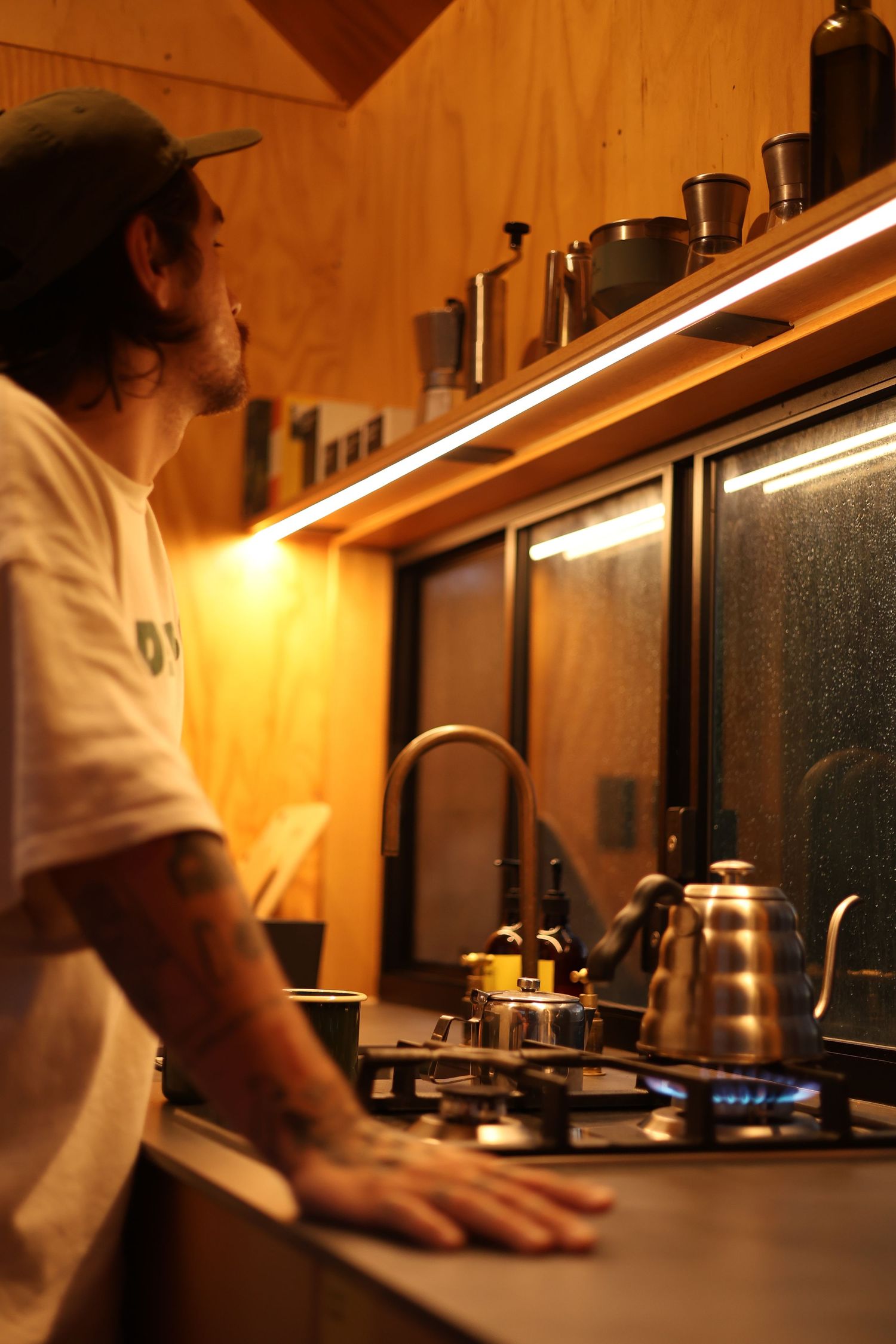 Warm lighting illuminates a rustic wooden countertop with kitchen equipment in a dimly lit space.