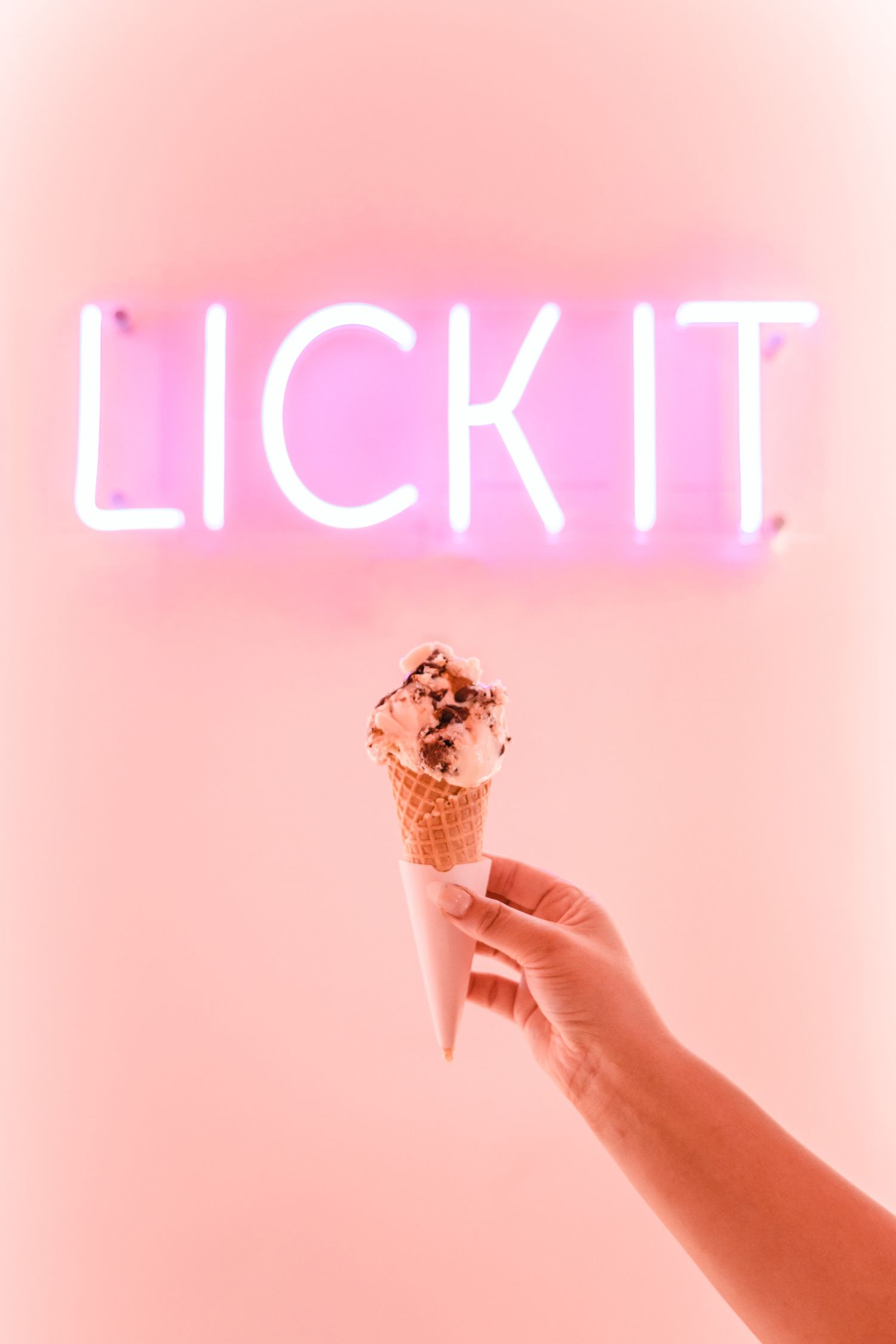 Illuminated neon 'LIGHT' sign glowing against a soft pink wall.