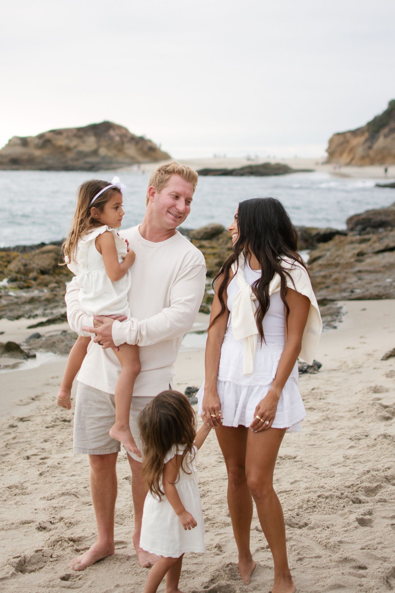 Family of four enjoying a moment together on a scenic rocky beach.