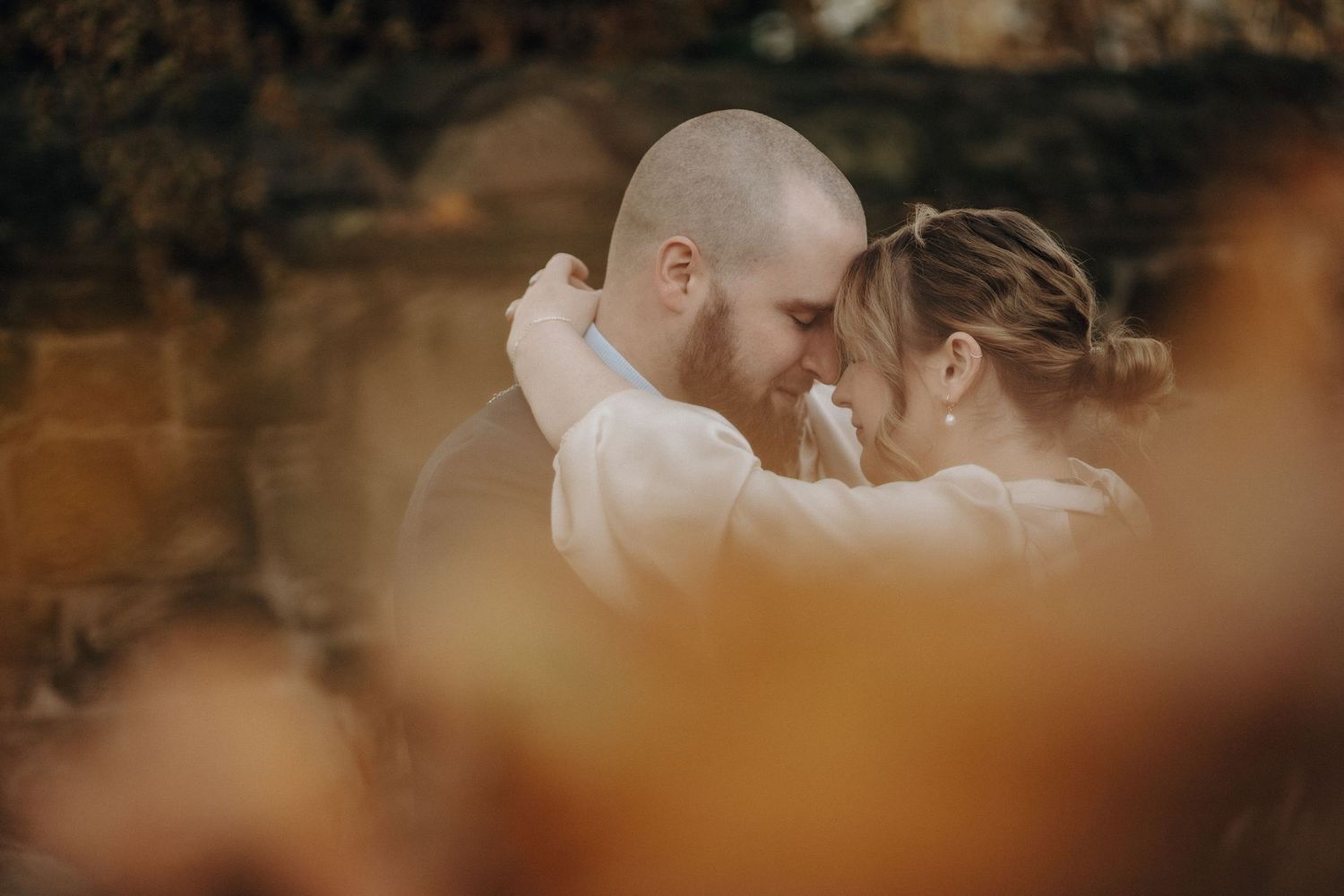 A tender moment between newlyweds as they embrace in warm autumn lighting.