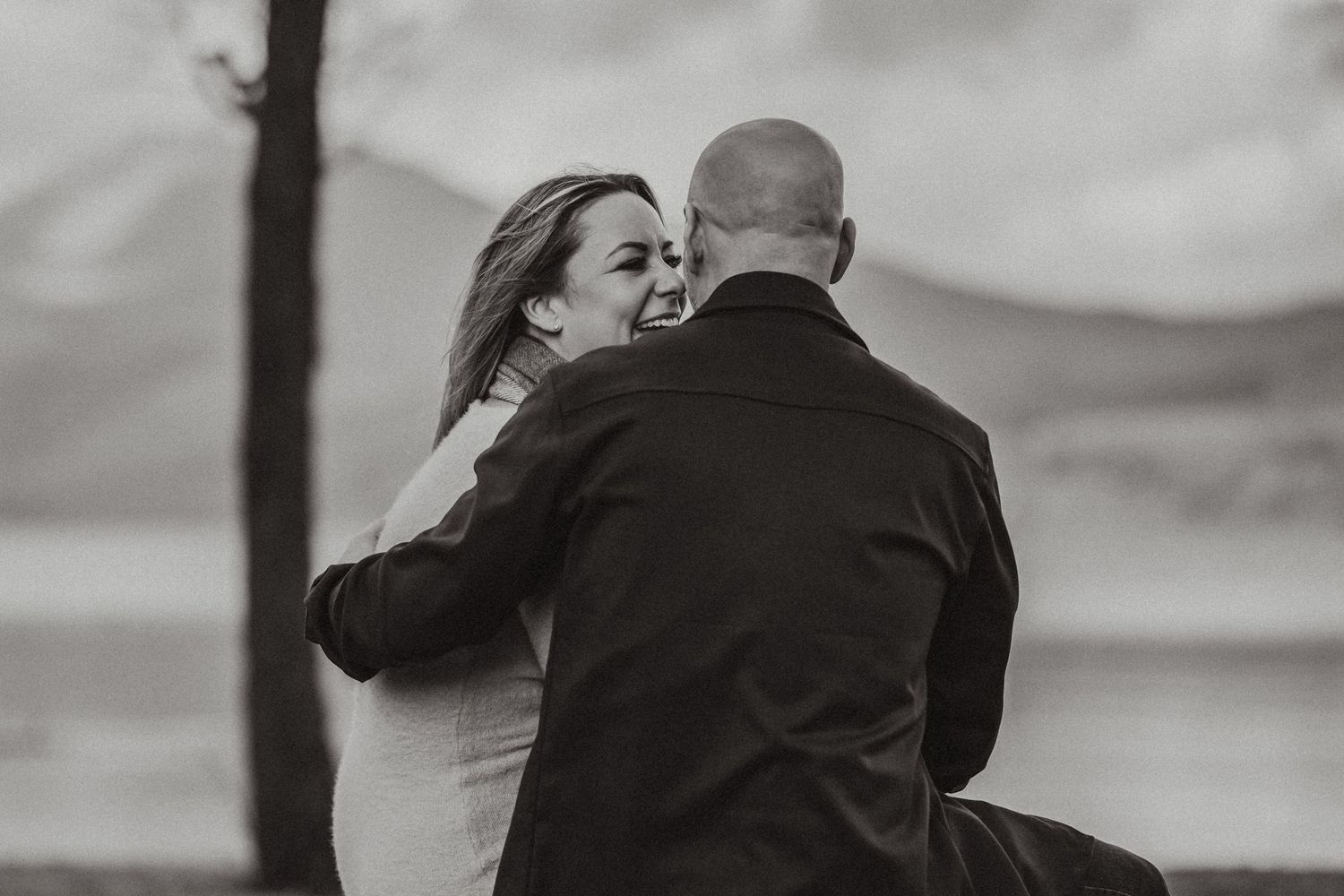 Romantic black and white photo of couple sharing tender moment by lakeside.