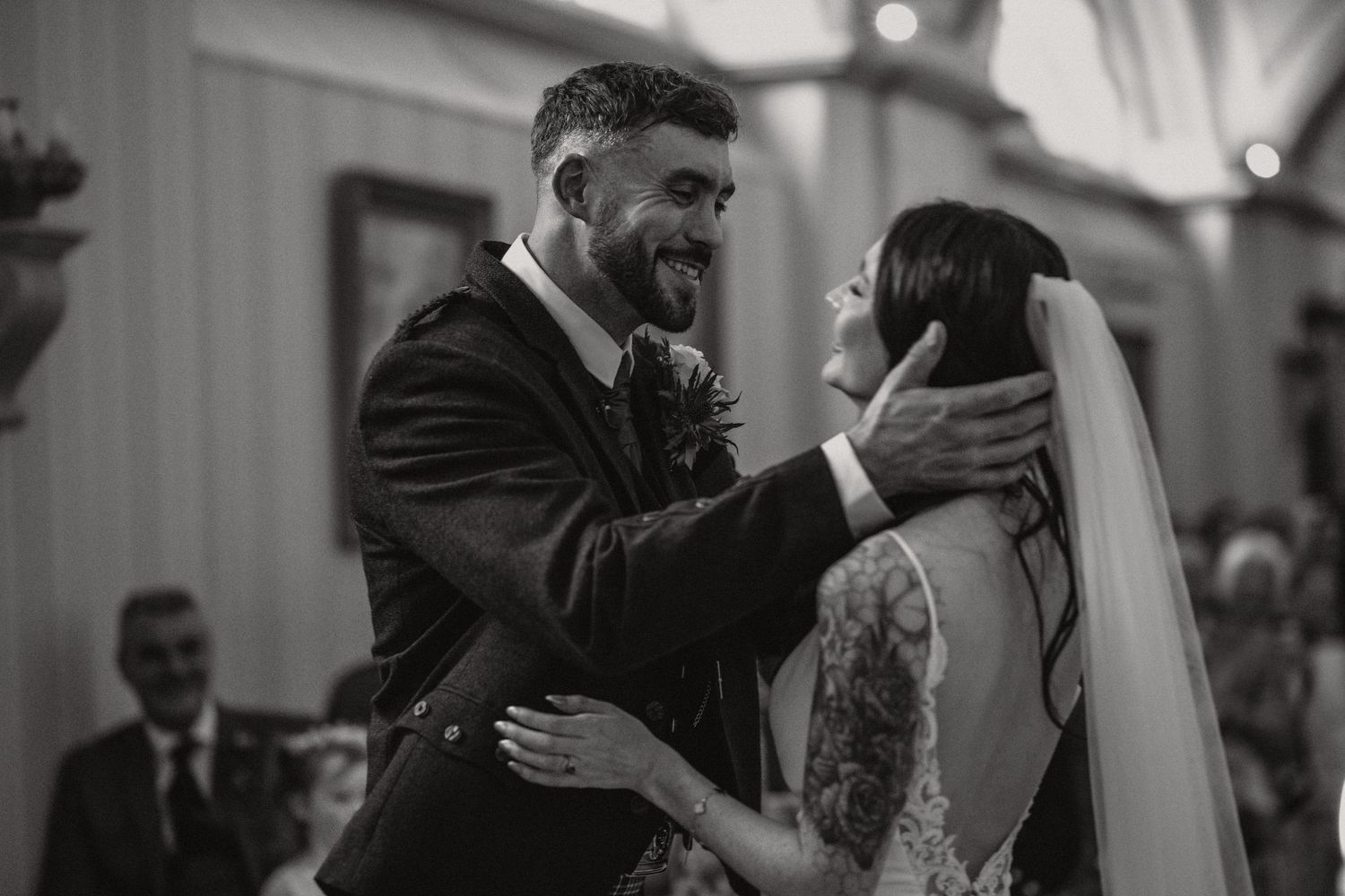 Intimate black and white moment captured between newlyweds during their wedding celebration.