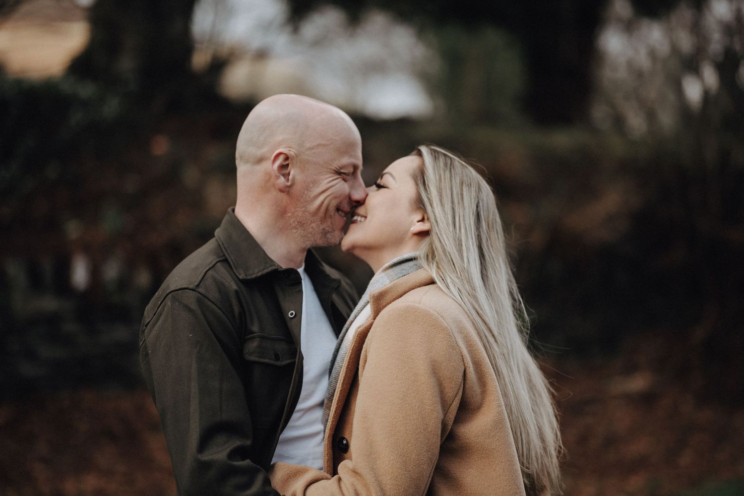 Close-up shot of couple sharing kiss during autumn outdoor photoshoot.