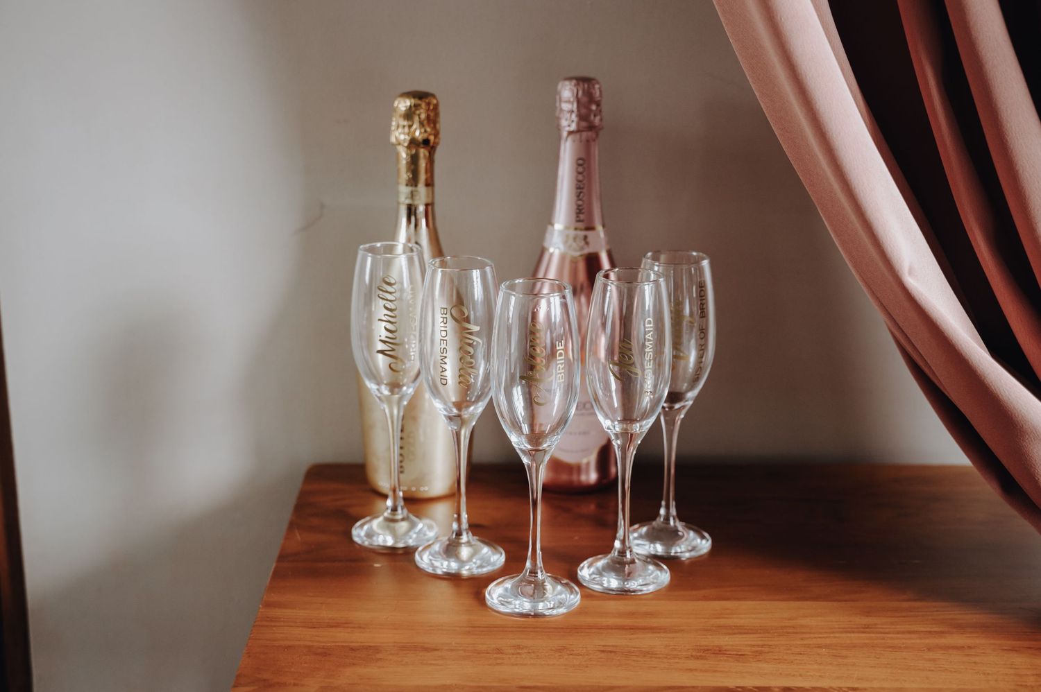 Champagne bottles and crystal flutes arranged elegantly on wooden table for wedding celebration.