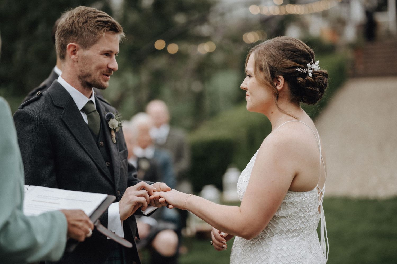 Couple exchanges rings during intimate outdoor garden wedding ceremony.