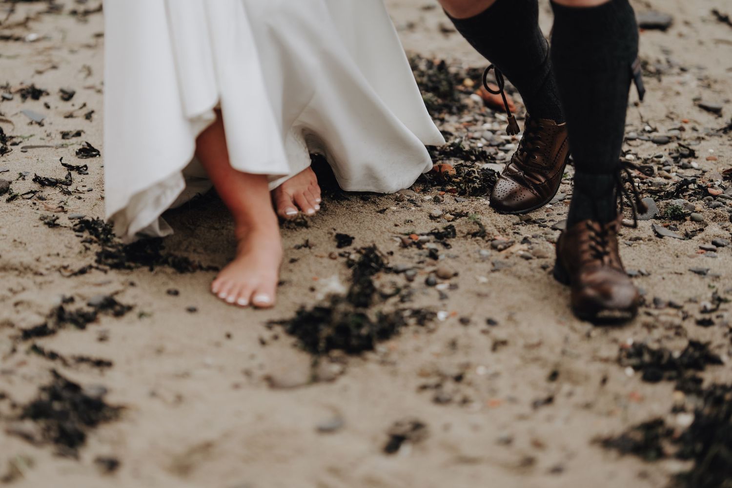 Close-up view of feet showing a wedding dress and dress shoes on stone steps.