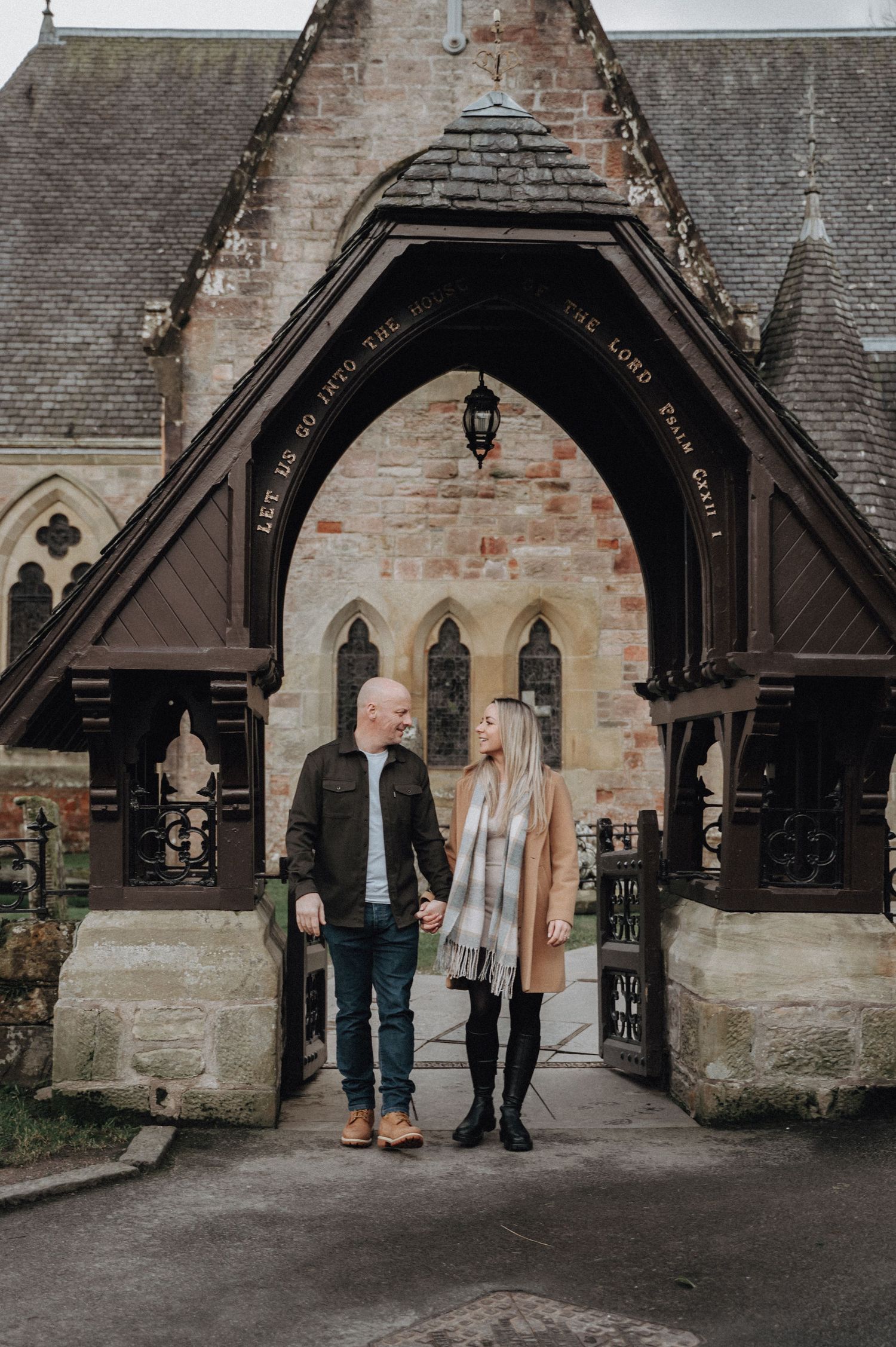 Couple standing under gothic church archway during romantic photoshoot.
