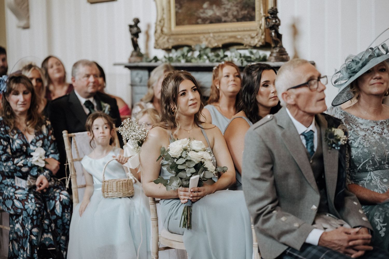 Wedding guests and bridesmaids dressed elegantly watching the ceremony in a decorated venue.